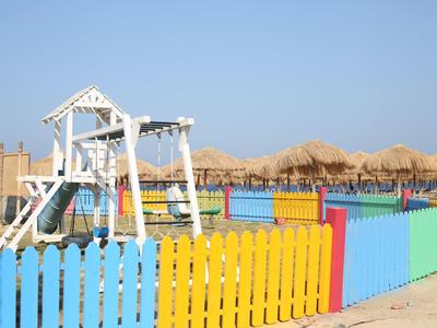 Clôture colorée autour d'une balançoire pour enfants sur la plage sous un ciel bleu.