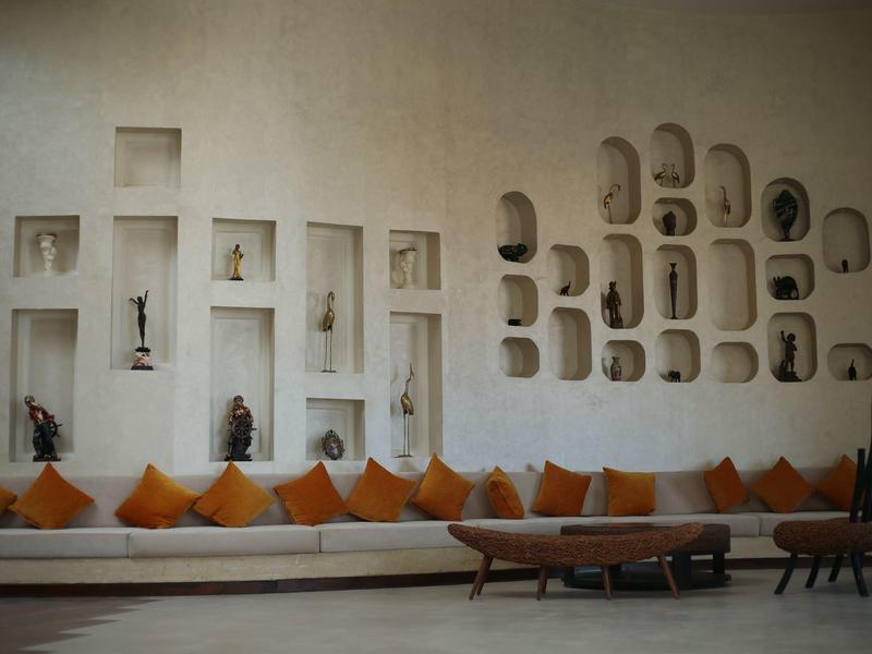 Salon moderne avec étagères murales intégrées, coussins orange et banc en bois