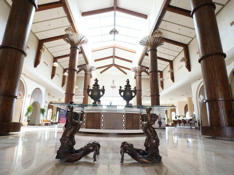 Grande hall d'hôtel avec de grandes colonnes en bois et un comptoir de réception central en arrière-plan