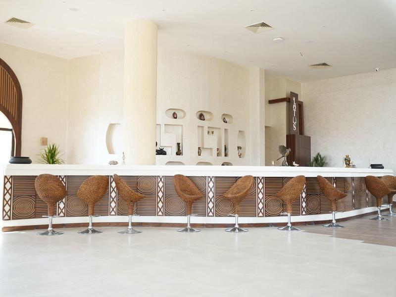 Espace bar d'hôtel moderne avec tabourets hauts et comptoir blanc dans une pièce lumineuse