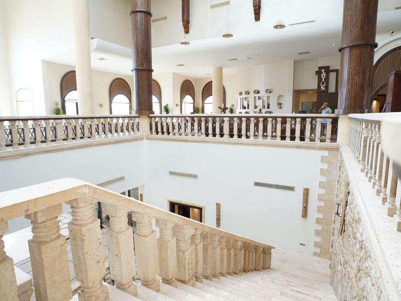 Hall d'hôtel lumineux avec escalier en marbre et rampe décorative, pièce spacieuse avec arches.