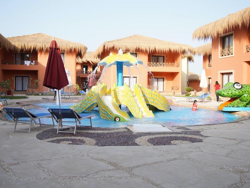 Des enfants jouent dans la piscine avec de grands toboggans et un jouet crocodile dans un hôtel.