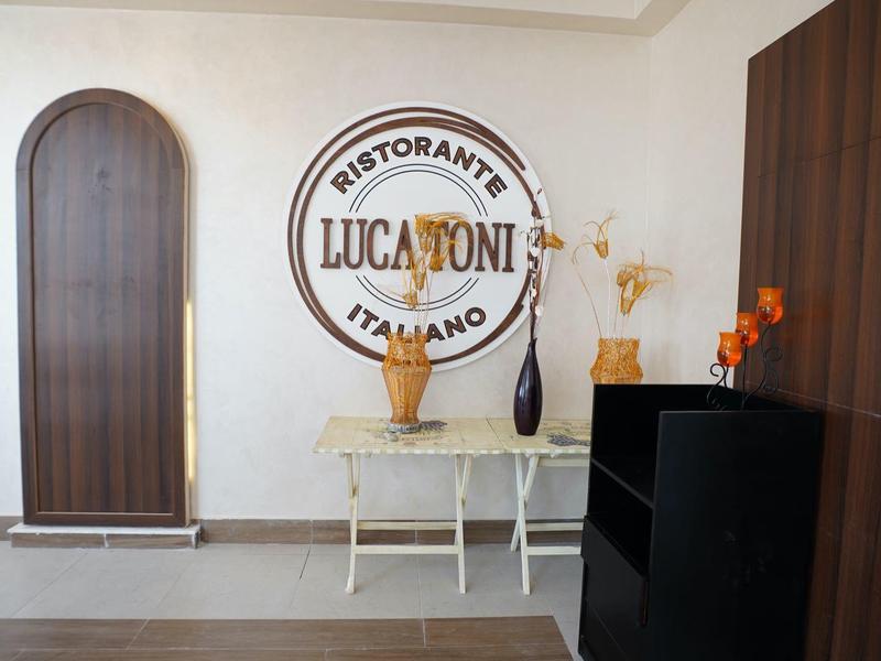 Entrée moderne d'un restaurant italien avec une décoration murale et une table avec des vases.