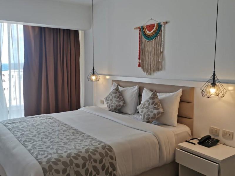 Chambre d'hôtel moderne avec lit double, coussins décoratifs subtils et sol en bois chaleureux.