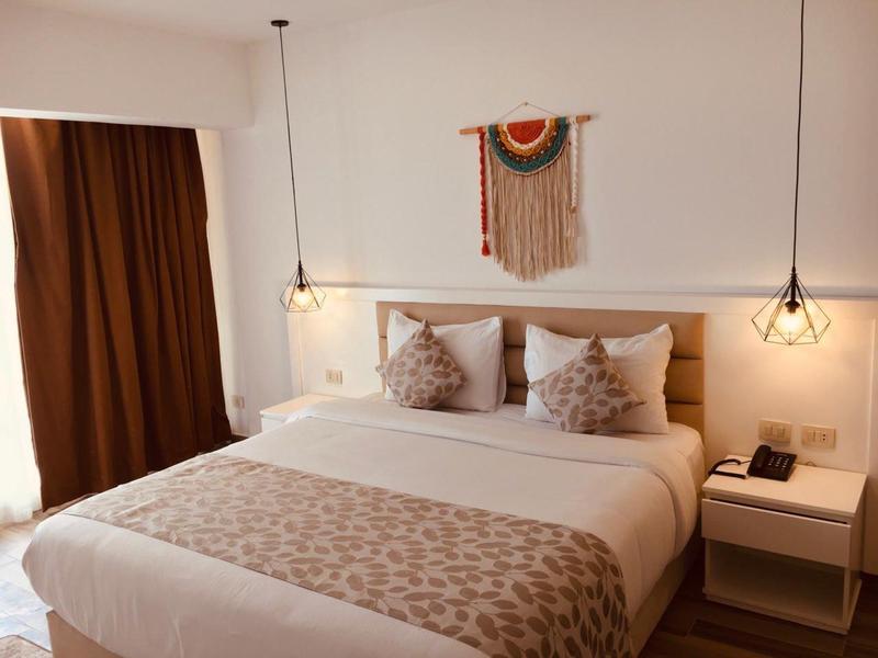 Chambre d'hôtel confortable avec grand lit, deux tables de nuit et lumière chaude.