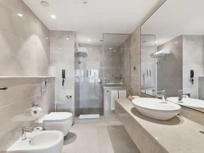 Helles, modernes Badezimmer mit bidet, WC, Doppelwaschbecken und integriertem Duschbereich.