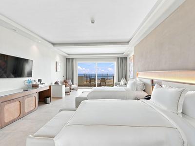 Modernes Hotelzimmer mit zwei großen Betten, TV und Balkon mit Meerblick.