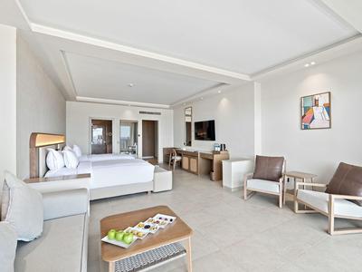 Helles Hotelzimmer mit Doppelbett, Sitzecke, Tisch und moderner Einrichtung.