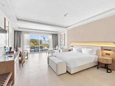 Helles Hotelzimmer mit Doppelbett, moderner Dekoration und Blick auf eine Terrasse.