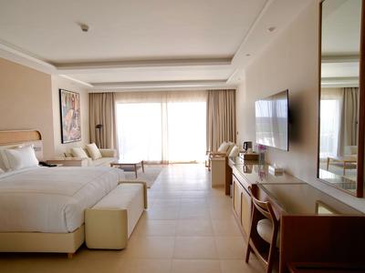 Modern eingerichtetes Hotelzimmer mit großem Bett, Sitzbereich und TV an der Wand.
