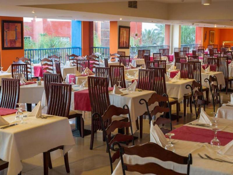 Elegancka sala restauracyjna z nakrytymi stołami i ciemnymi drewnianymi krzesłami.