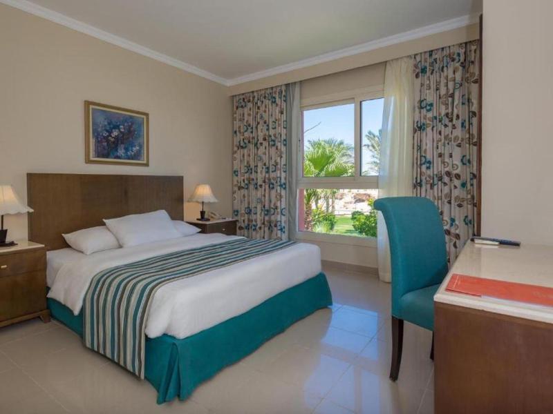 Jasny pokój hotelowy z dużym łóżkiem i widokiem na ogród.