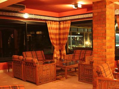 Zona salotto accogliente con poltrone imbottite e tavolo in un hotel con grandi finestre.