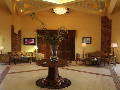 Elegante hall d'hotel con tavolo centrale e grande composizione floreale, divani e illuminazione calda.