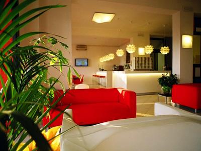 Moderne Hotellobby mit roten Sofas, Pflanzen und warmem Licht.
