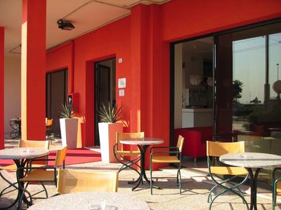 Terrassenbereich eines Hotels mit roten Wänden und Tischen im Freien.