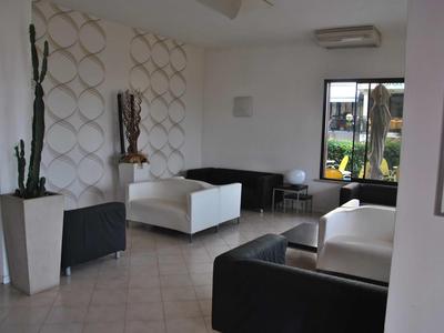 Moderne Hotellobby mit weißen und schwarzen Sofas, Pflanzen und einem großen Fenster.