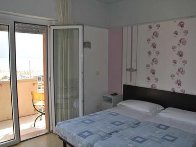 Camera da letto con letto matrimoniale, porta scorrevole in vetro e balcone con vista esterna.