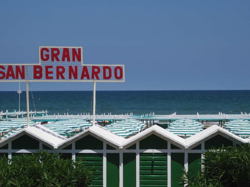 Casa da spiaggia verde con vista mare e ombrelloni con insegna Gran San Bernardo.