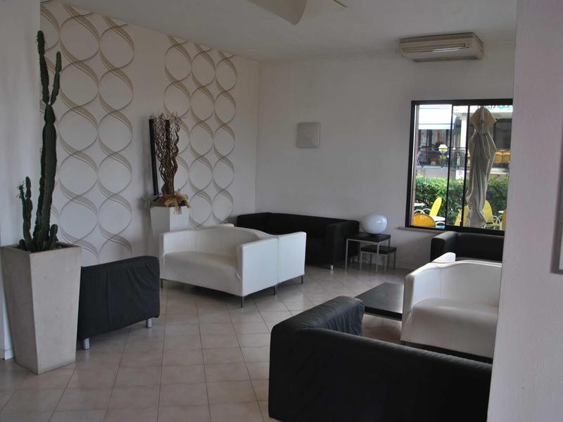 Camera d'hotel moderna con divani bianchi e neri, decorazioni e vista dalla finestra.