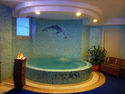 Runder Whirlpool in einem Raum mit blauen Fliesen, einer Pflanze und einer Sitzbank.