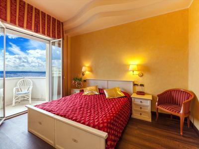 Gemütliches Hotelzimmer mit rotem Bett, Balkon und Meerblick.