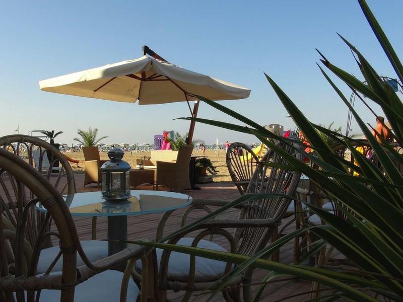 Dachterrasse mit Sonnenschirm, Stühlen, Tischen und Pflanzen bei klarem Himmel.