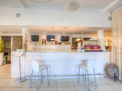 Moderner Thekenbereich mit zwei Metallstühlen, weißen Fliesen und warmem Licht im Raum.