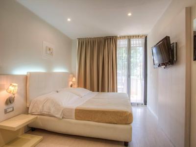 Modern eingerichtetes Hotelzimmer mit Doppelbett, Fernseher und großem Fenster mit Vorhängen.