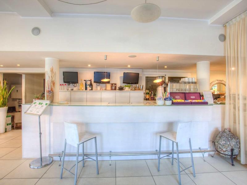 Moderner Thekenbereich mit zwei Metallstühlen, weißen Fliesen und warmem Licht im Raum.