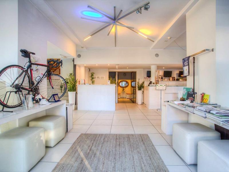 Moderner heller Raum mit weißem Interieur, Sofa, Fahrrad an der Wand und Küchenzeile im Hintergrund.