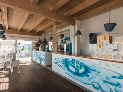 Bright beach bar with wooden ceiling, white and blue counters, and nautical decor.