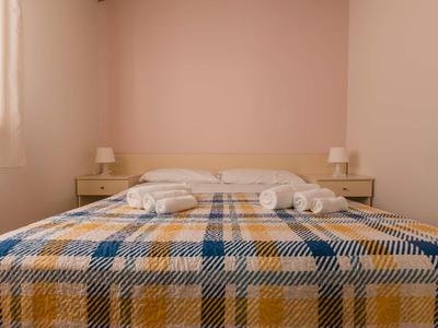 A double bed with a plaid bedspread and two bedside tables in a bright, minimalist room.