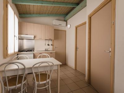Small kitchenette with table and chairs, beige doors, and green ceiling.