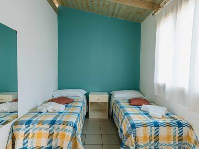 Room with two single beds, blue and white checkered bedspreads, and a nightstand between them.