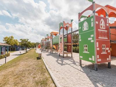 Colorful large playground with climbing frames and slides beside a walkway.