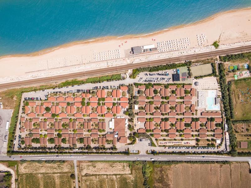 Aerial view of a beach resort with red roofs and a swimming pool.