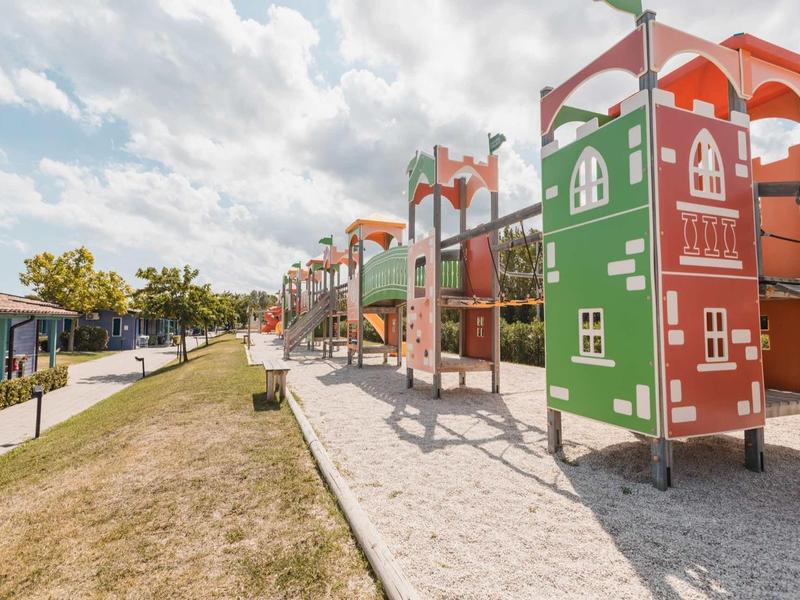 Colorful large playground with climbing frames and slides beside a walkway.