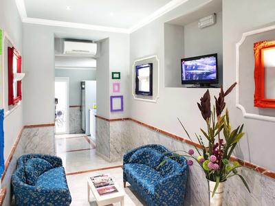 Moderner Hotelflur mit bunten Bilderrahmen und blauen Sesseln neben einem Blumengesteck.