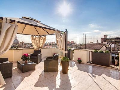 Dachterrasse mit Sitzbereich, Pavillon, Pflanzen und Blick auf Gebäudekulisse bei Sonnenschein.