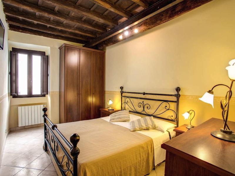 Gemütliches Schlafzimmer mit Holzbalkendecke, gelben Wänden, Eisenbett und Holzmöbeln.