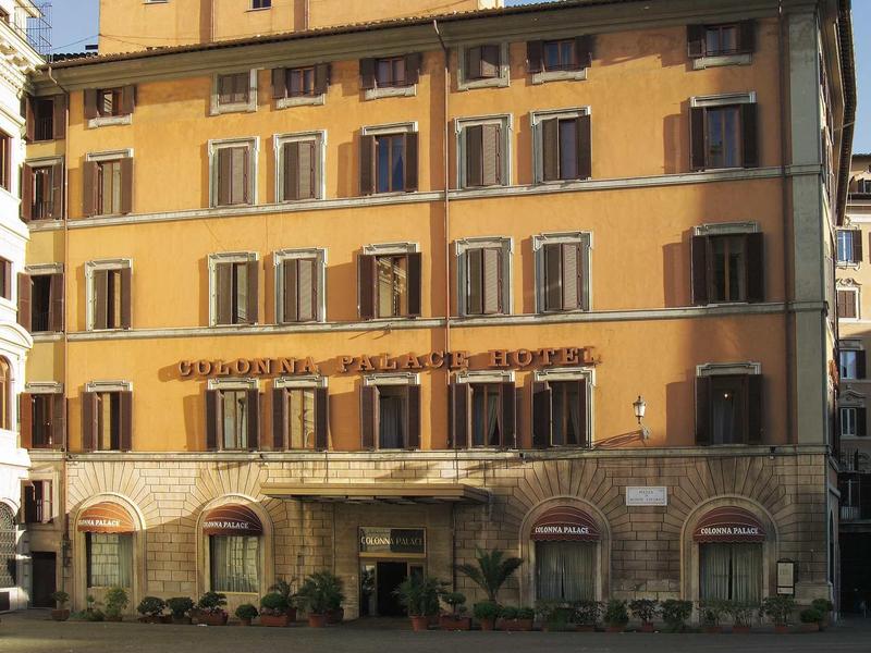 Gelbes mehrstöckiges Gebäude mit Holzfenstern und Arkaden im Erdgeschoss bei Abendlicht.