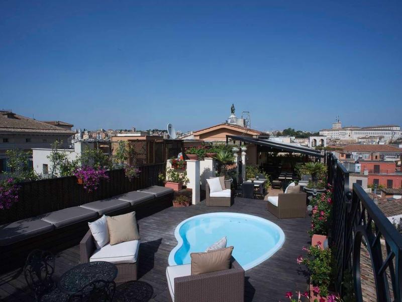 Dachterrasse mit kleinem Pool, Sitzbereich, Pflanzen und klarem blauem Himmel im Hintergrund.