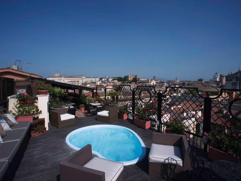 Dachterrasse mit kleinem Pool, Sitzmöbeln und Blick auf die Stadt bei klarem Himmel.