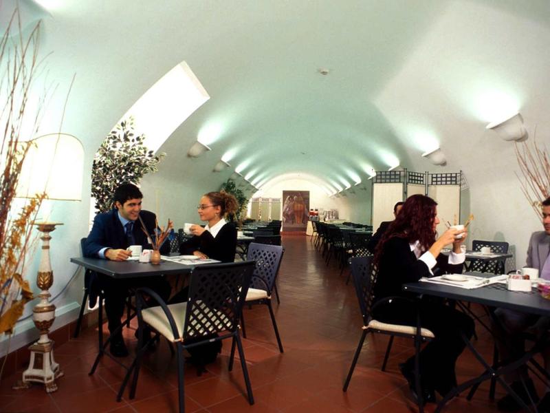 Innenraum eines Restaurants mit gewölbter Decke, Tischen und Gästen beim Essen.