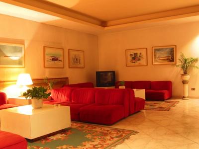 Bright living room with red sofas, rug, TV, and plants in a hotel.