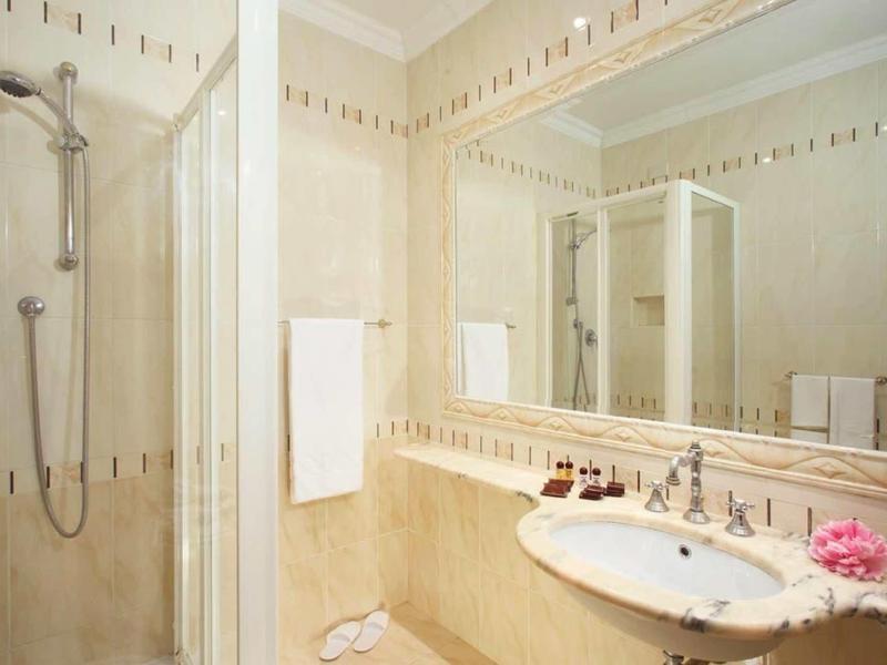 Modern bathroom with shower, sink, and large mirrors in a bright design.