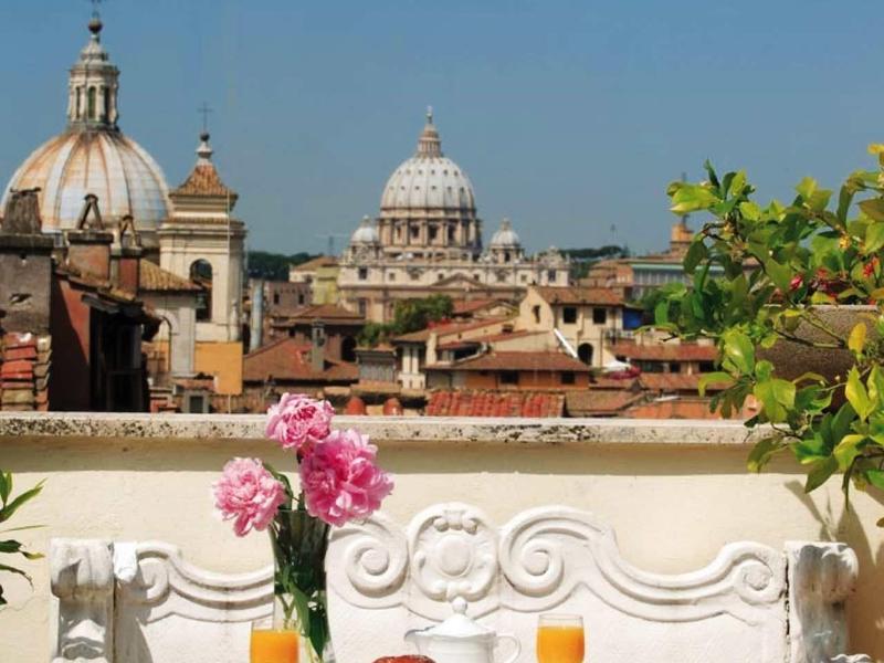 View from a terrace with a set breakfast table overlooking a city with historic domes.