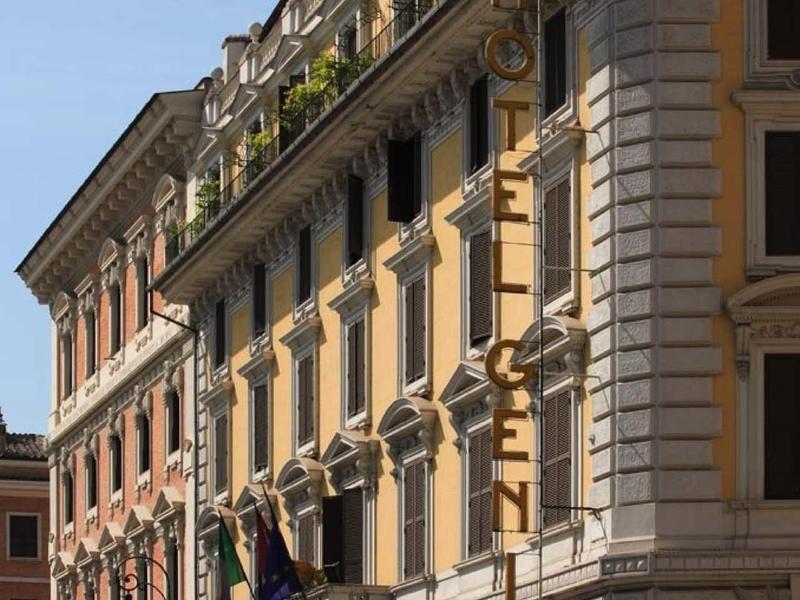 Historic hotel building with flags and balcony under clear sky.