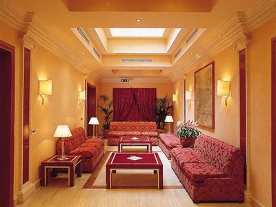 Einladender Hotel-Warteraum mit roten Sofas, Lampen und Beleuchtung an der Decke.